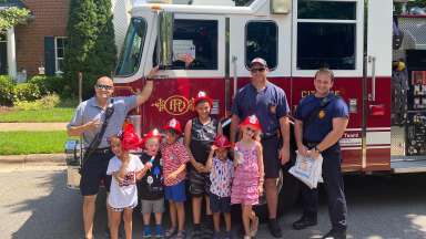 Firefighters and children posing in front of a Raleigh fire truck