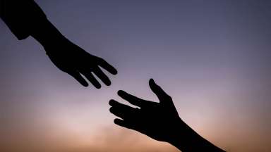 One hand is reaching down to take another person's hand