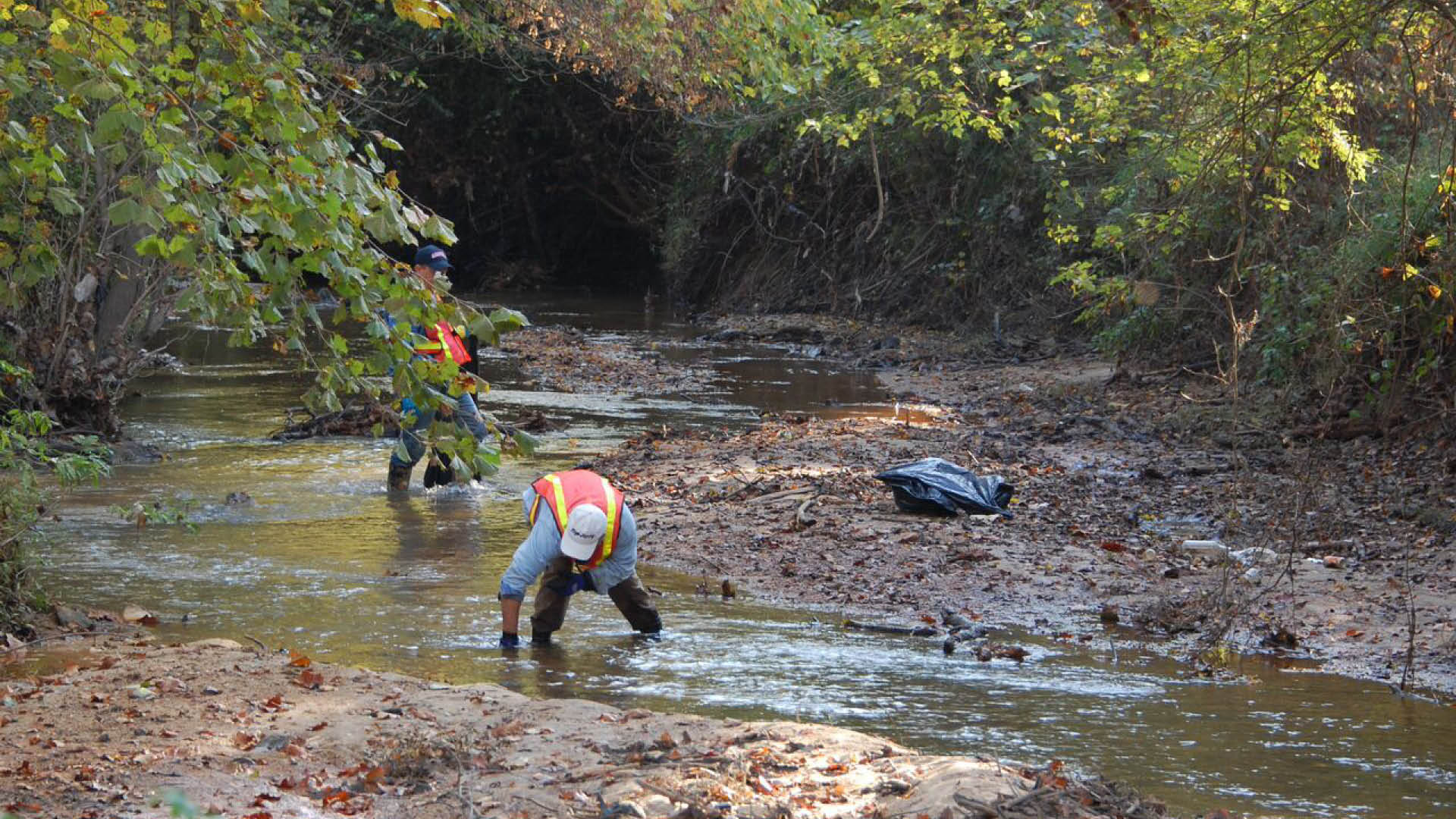 A volunteer picks up trash in a Raleigh stream to help reduce water pollution in our area.