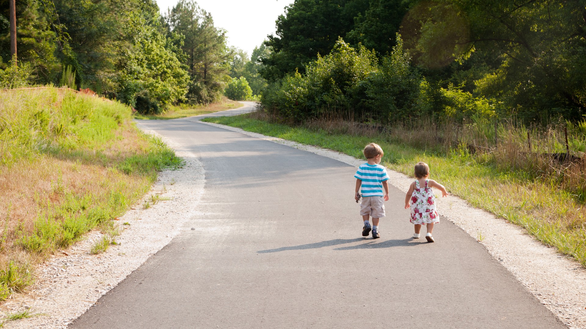 Two little kids walking along a greenway trail 