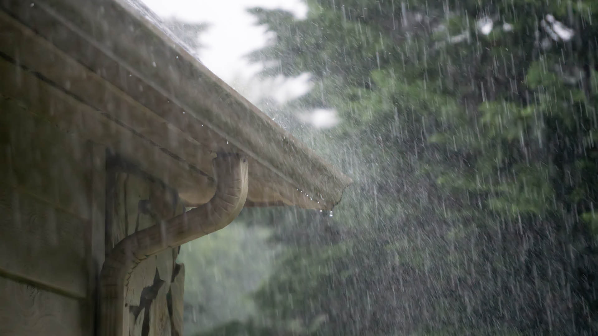 A photo of rain falling off a roof of a house