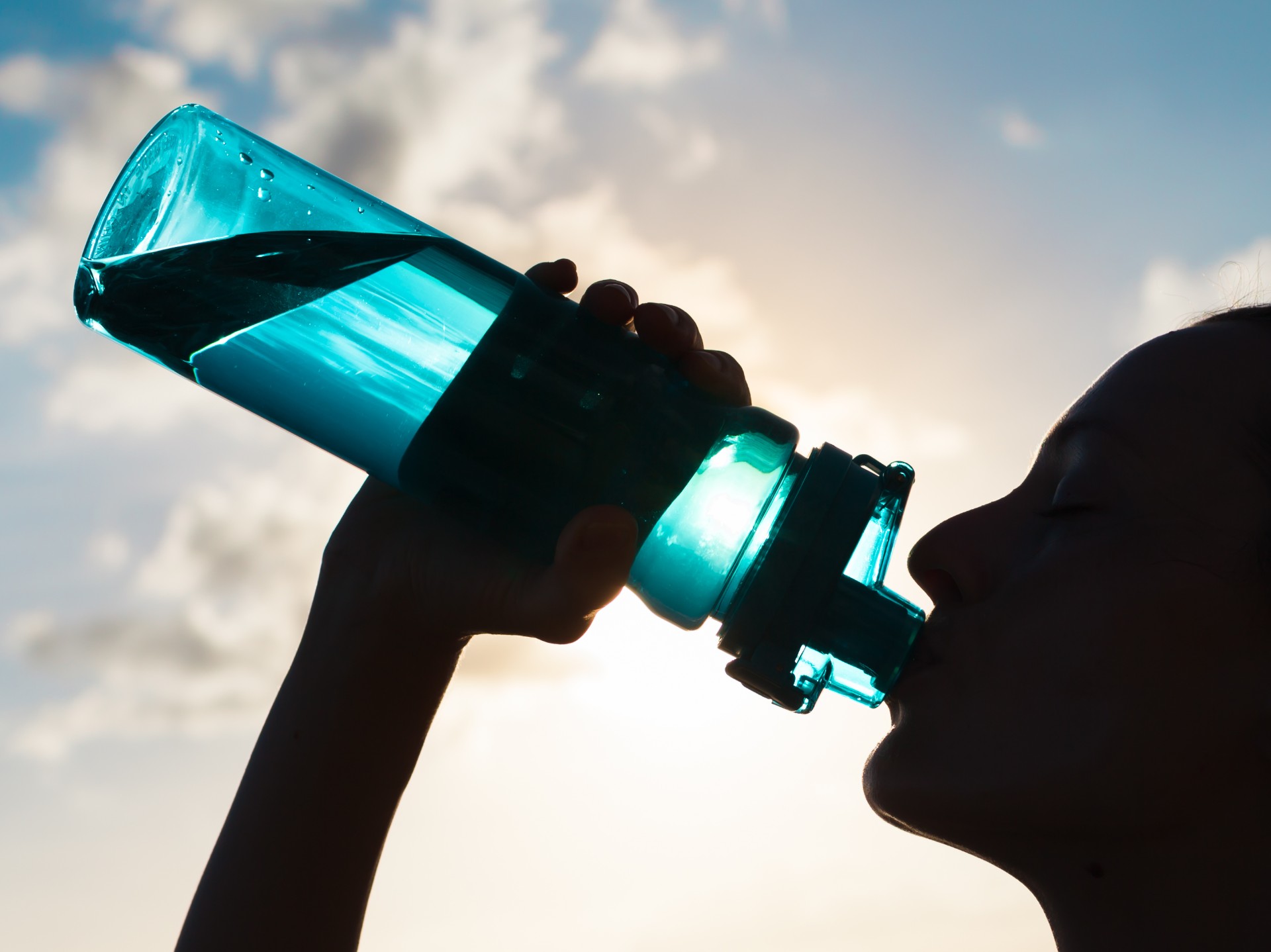 Woman drinking from water bottle in the sun