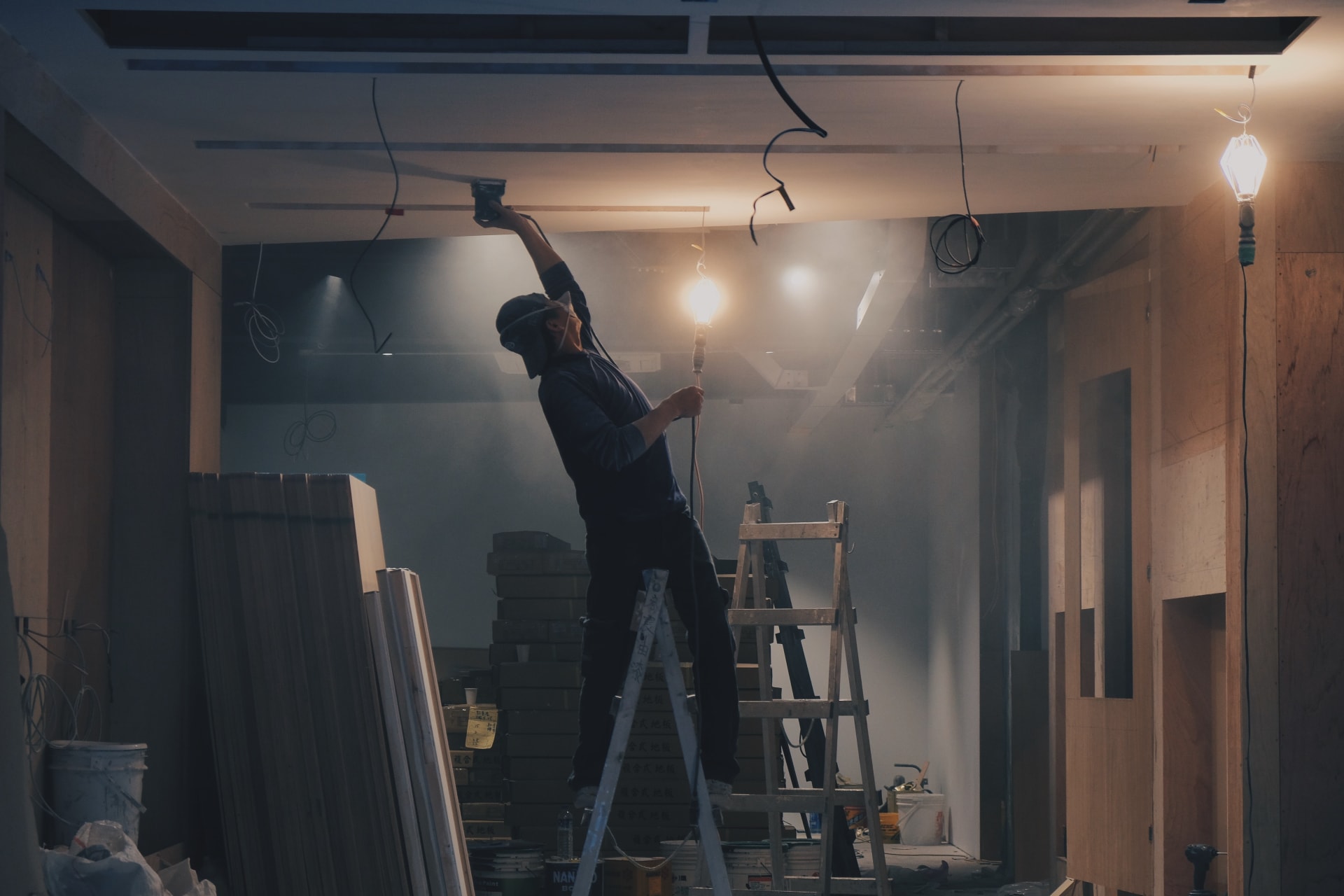 Man on ladder repairing white ceiling