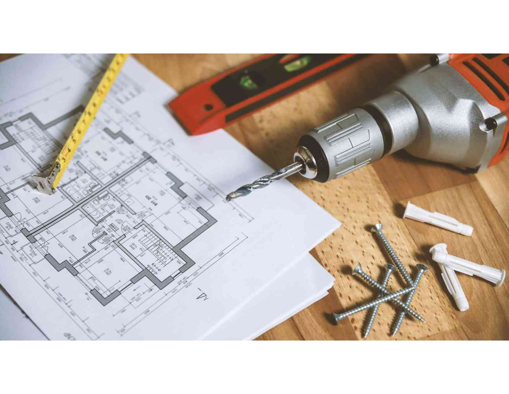 Image of plans, pencil, level, drill, and screws laying on a table