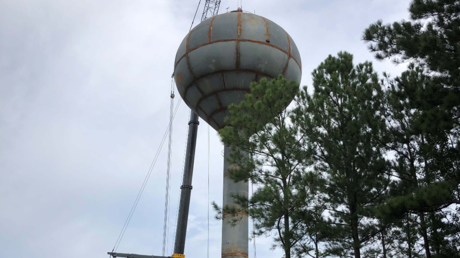 Crews place completed water tank on water tank structure.