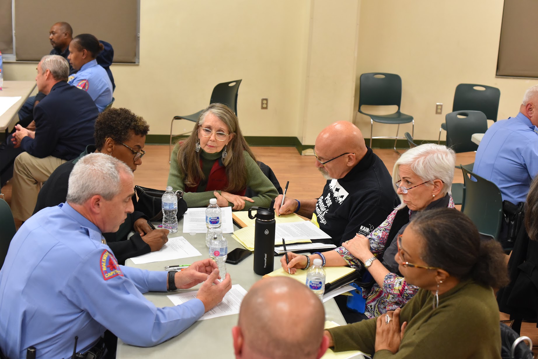 Police and community members gather at a table during a Police Advisory Board meeting 