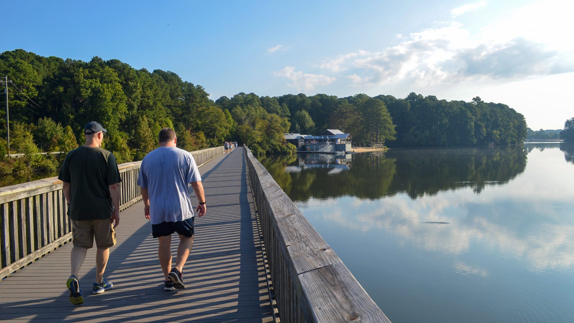 People walking on wooden boardwalk with view of lake and waterfront center