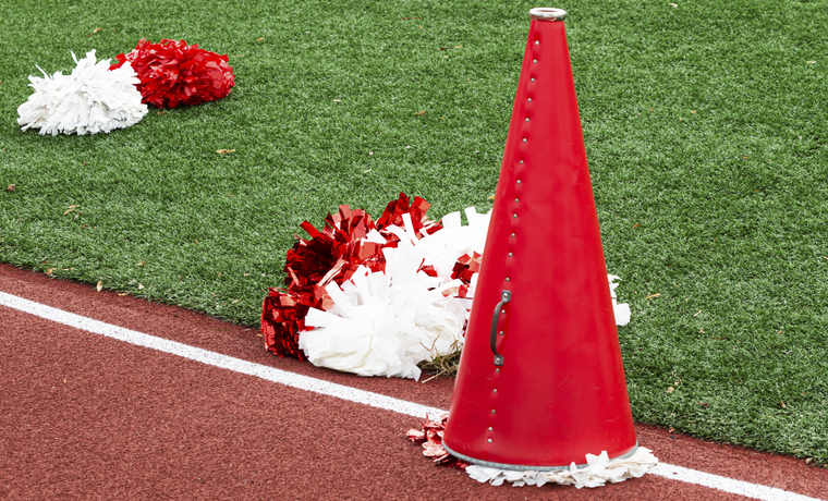 Image of a meagphone and pom poms on the ground on a track