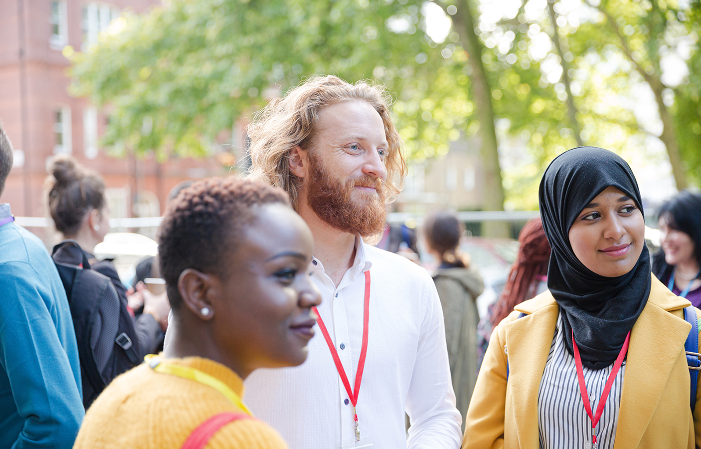 Three people of different ethnic backgrounds standing around with lanyards on