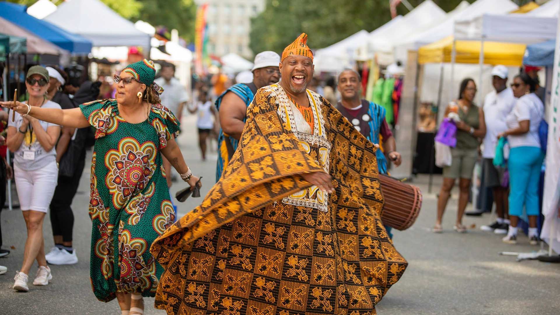 People dancing and playing drums while walking down the center of Fayetteville Street