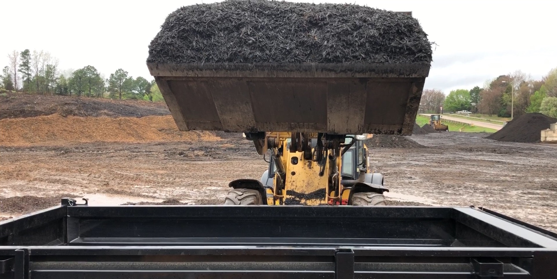 Bulldozer loading yard waste product onto trailer.