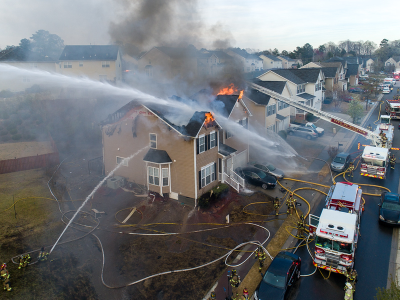 Home burning with fire trucks spraying home down with water