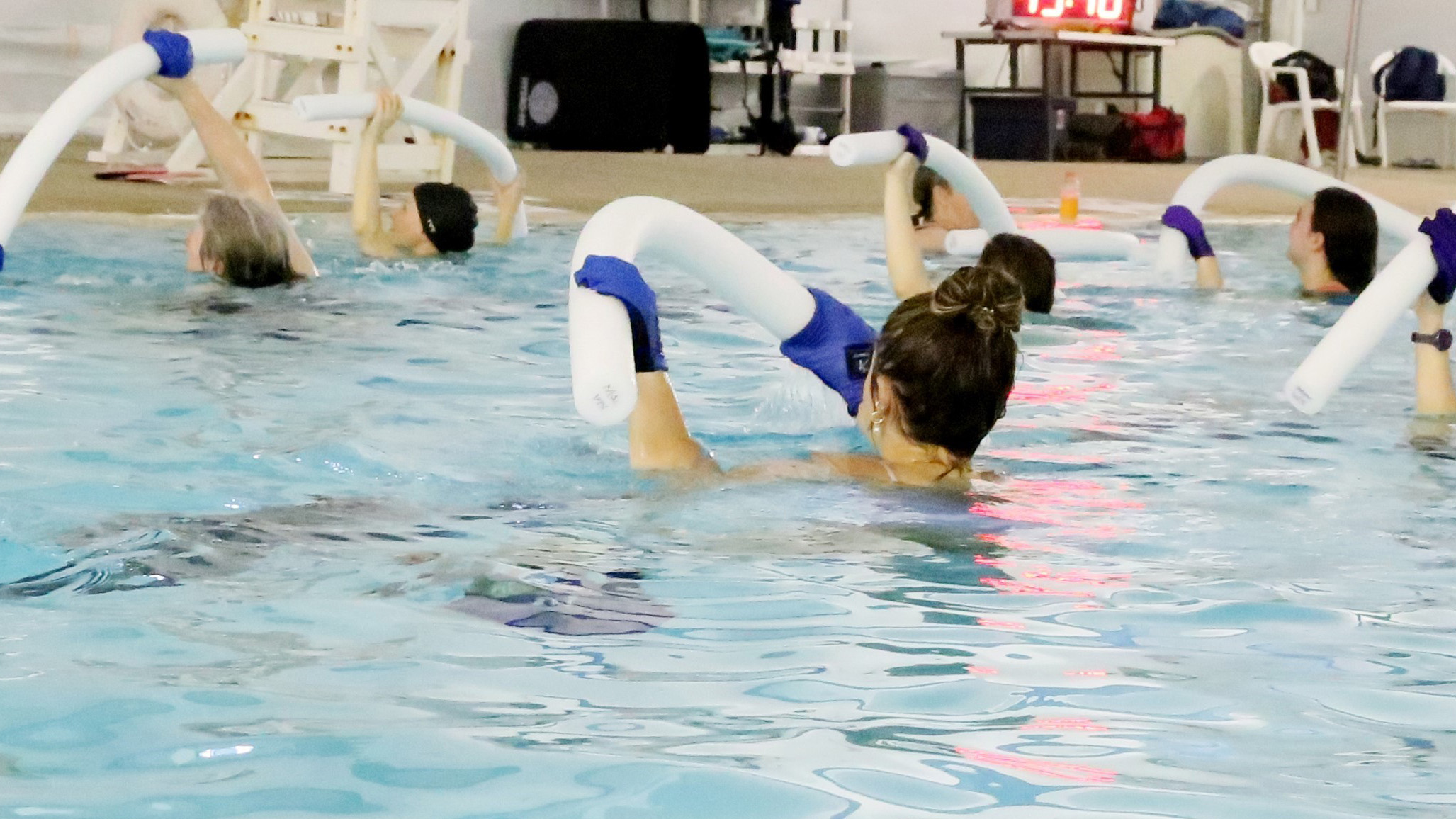 people in a pool with gloves and pool noodles