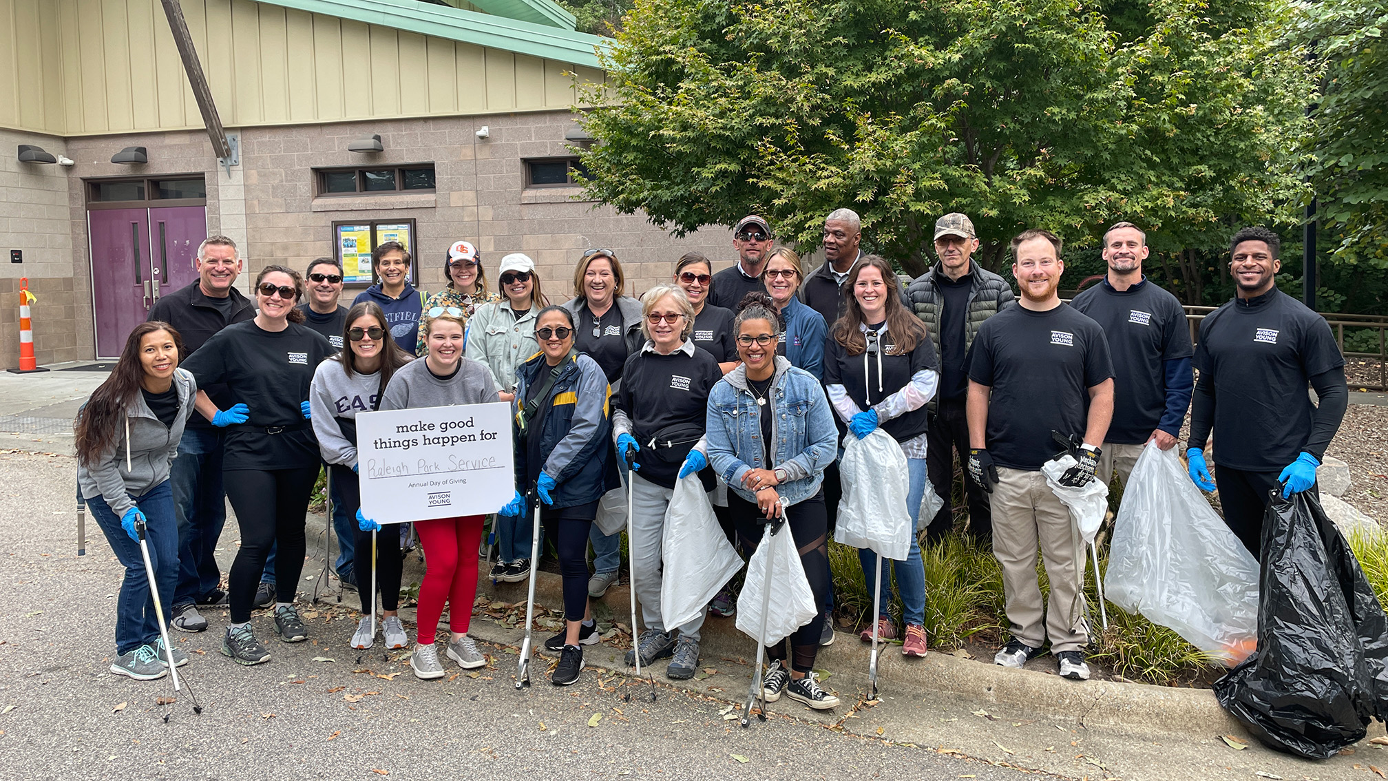 a group of smiling volunteers with litter grabbers and trash bags 