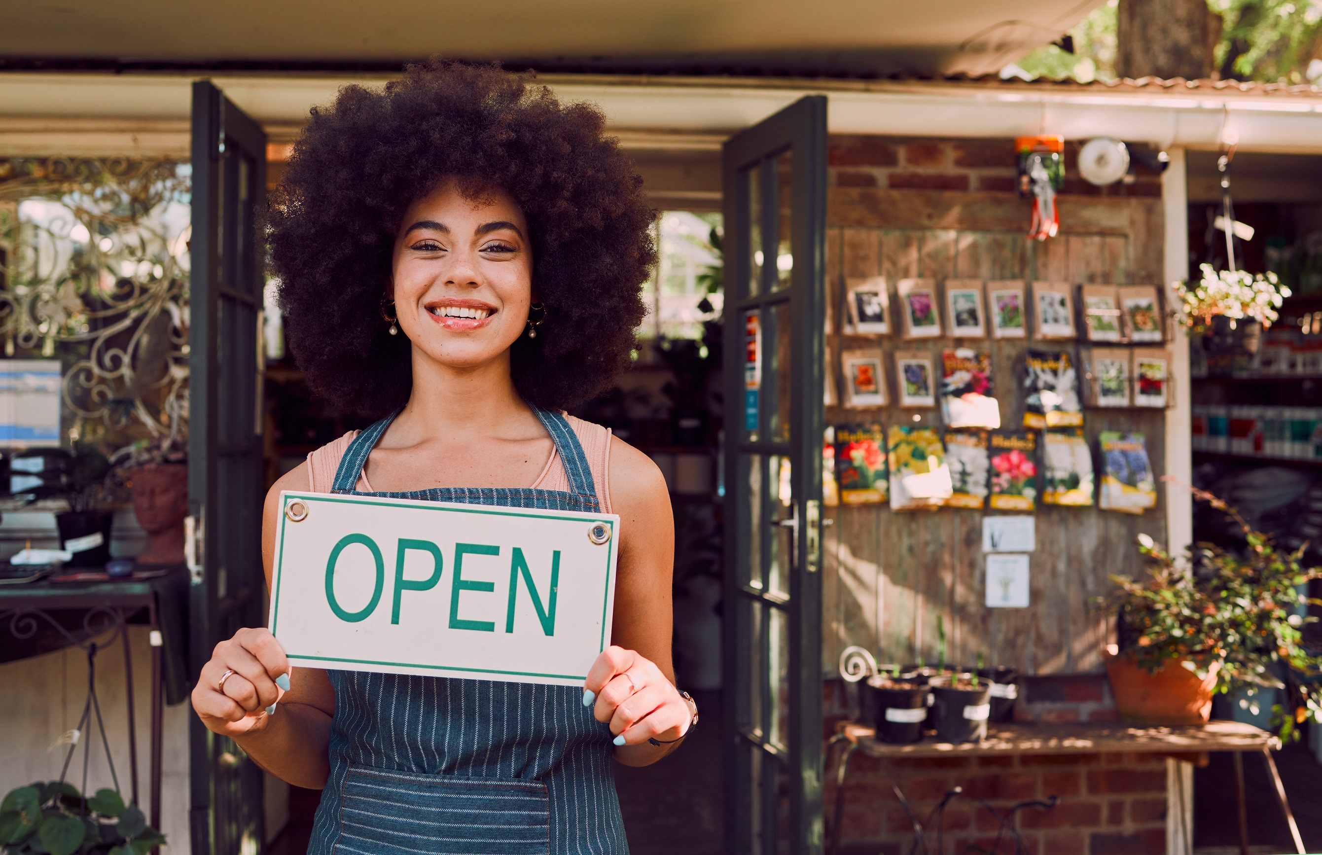 Woman holding open sign for small business garden