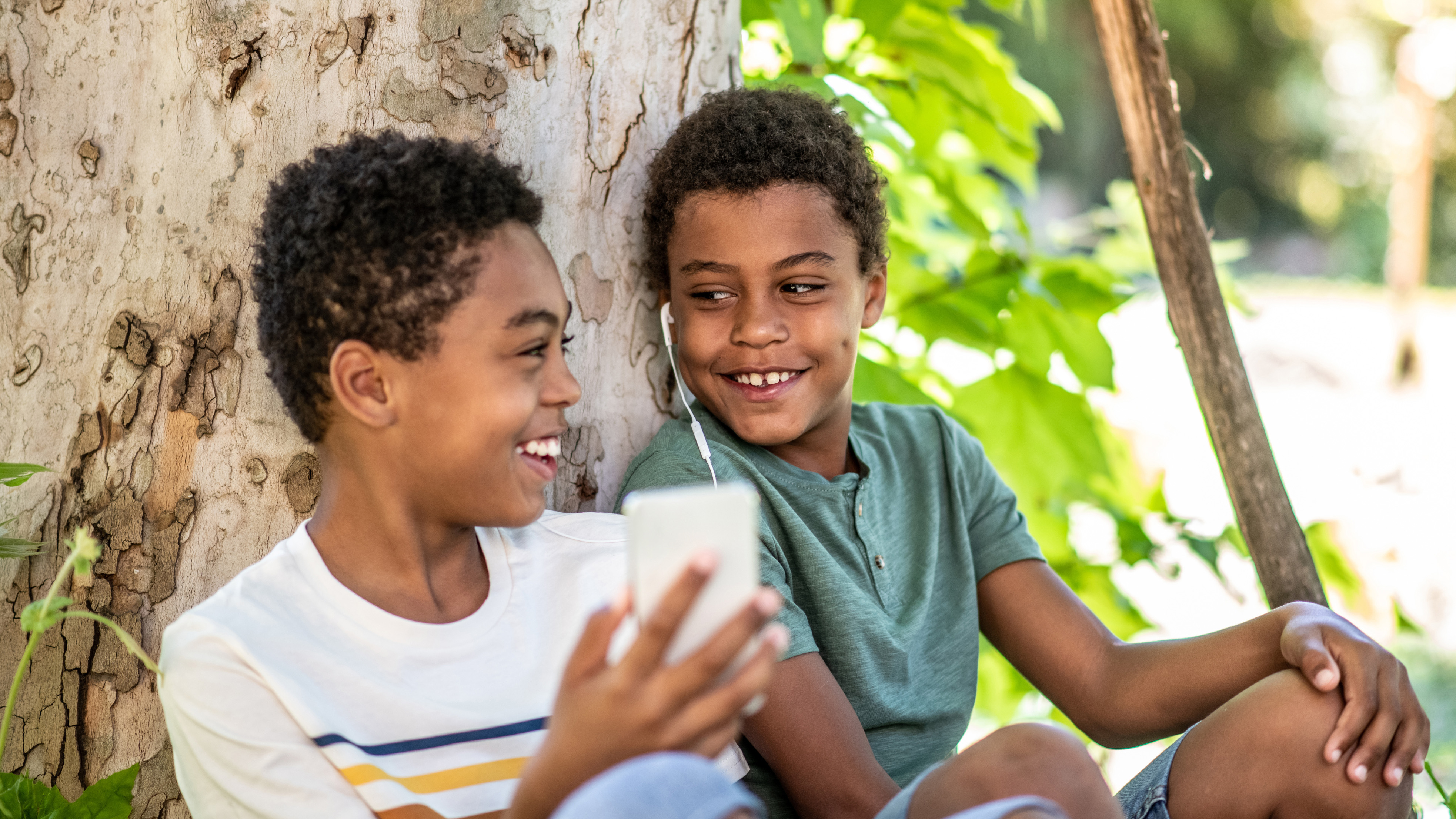 two children sitting under the tree shade