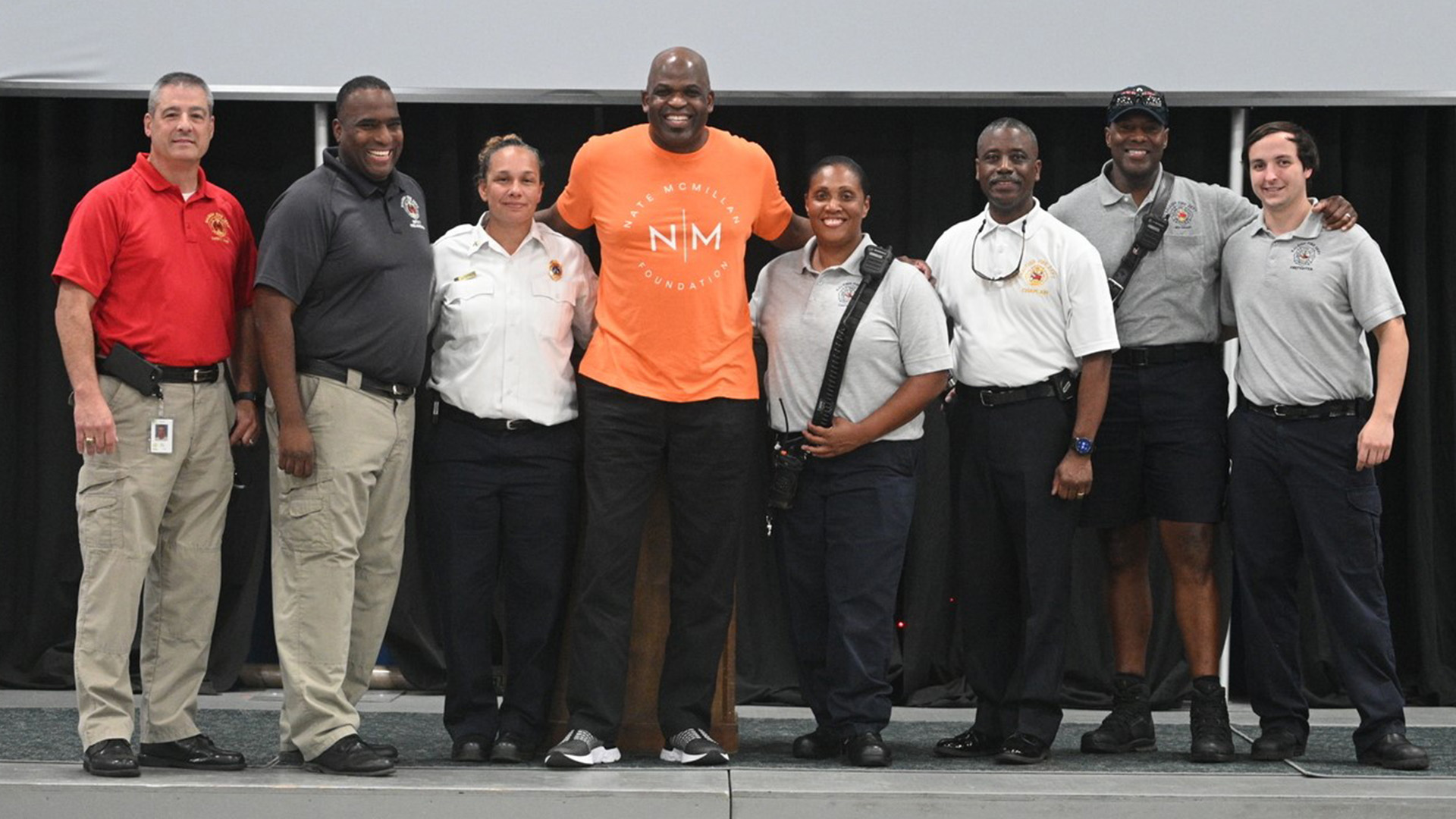 Members of the Raleigh Fire Department pose with former NBA player and coach Nate McMillan at the Nate McMillan Mentoring Camp.