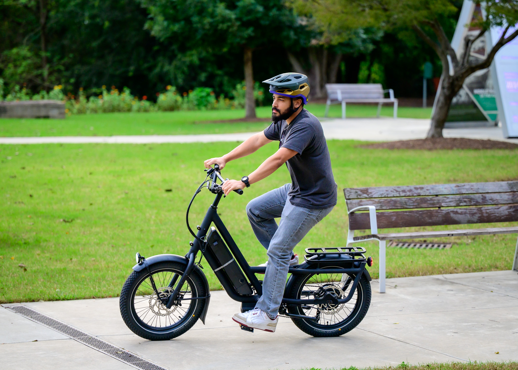 Adult male riding an e-bike on a sidewalk