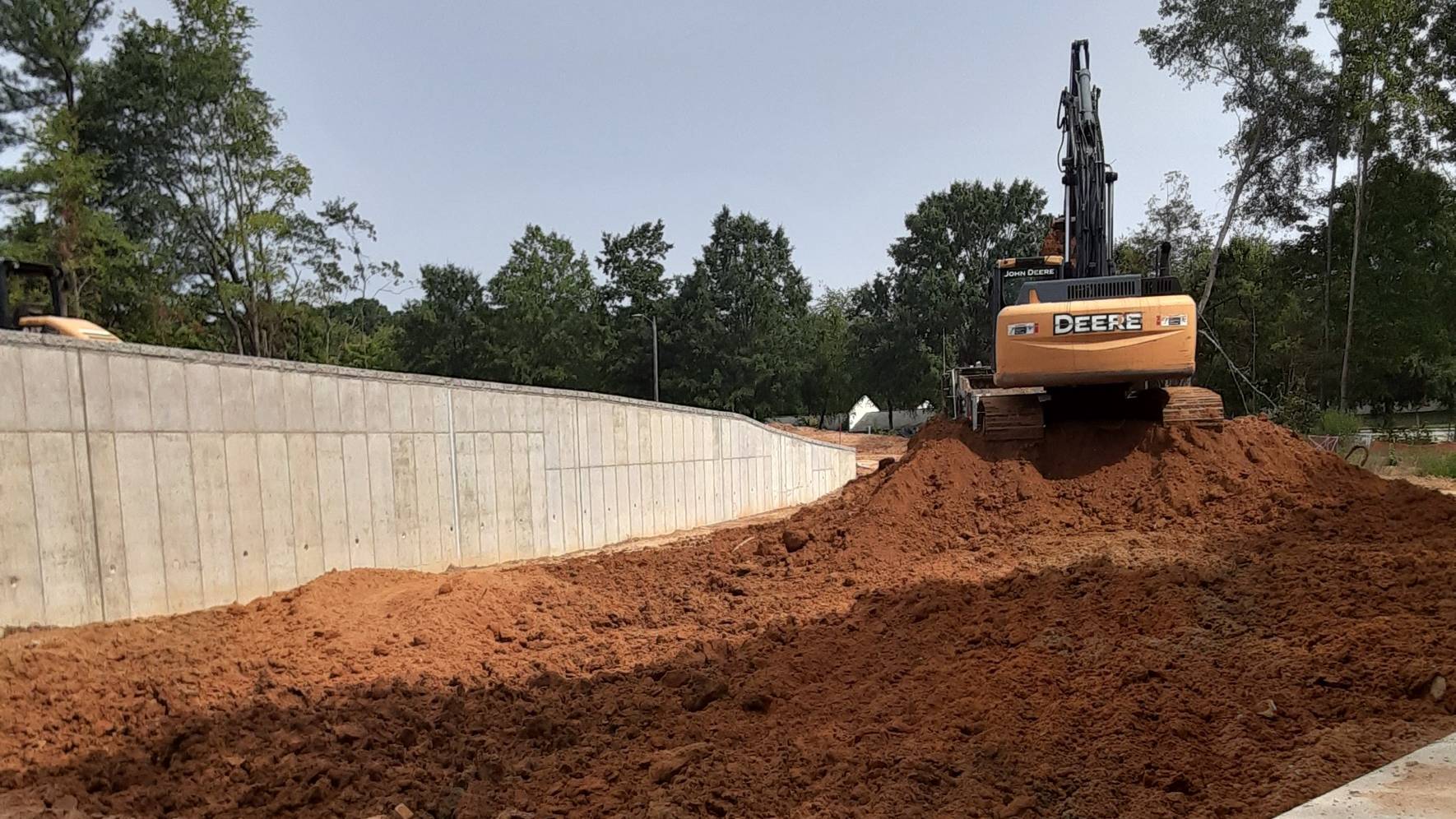 A bulldozer grades land surrounded by trees.