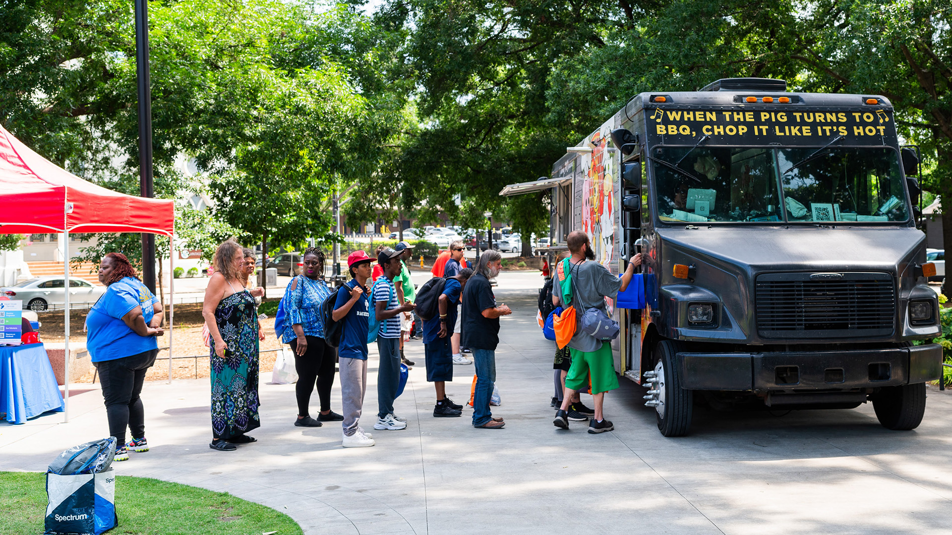People in line for a food truck at Moore Square with City of Raleigh tent and table nearby