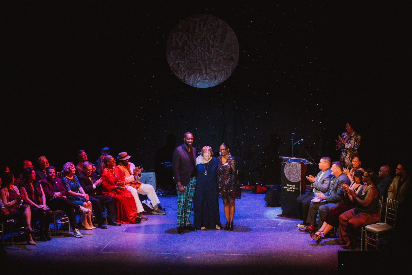 A group of people smiling for the camera onstage at an awards ceremony. 