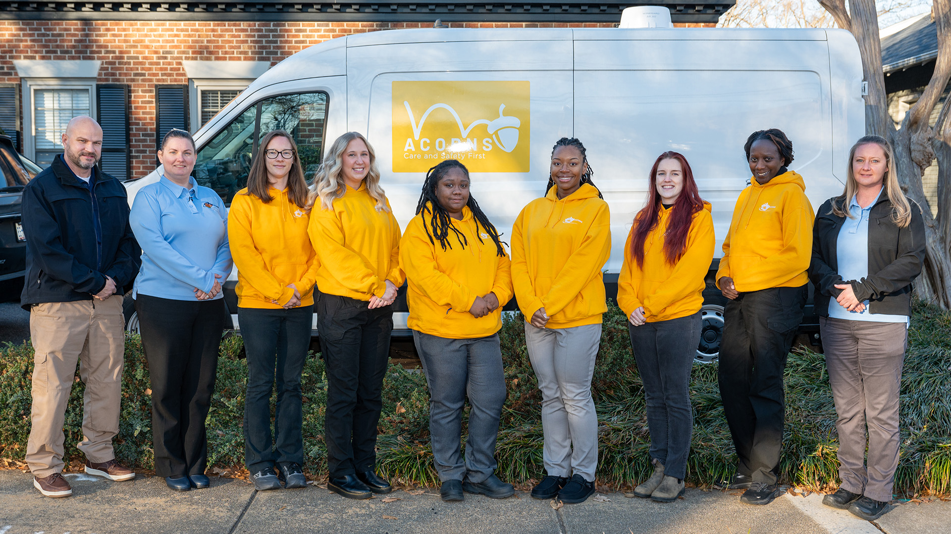 Members of the ACORNS team stand in front of a white van with the Acorns logo