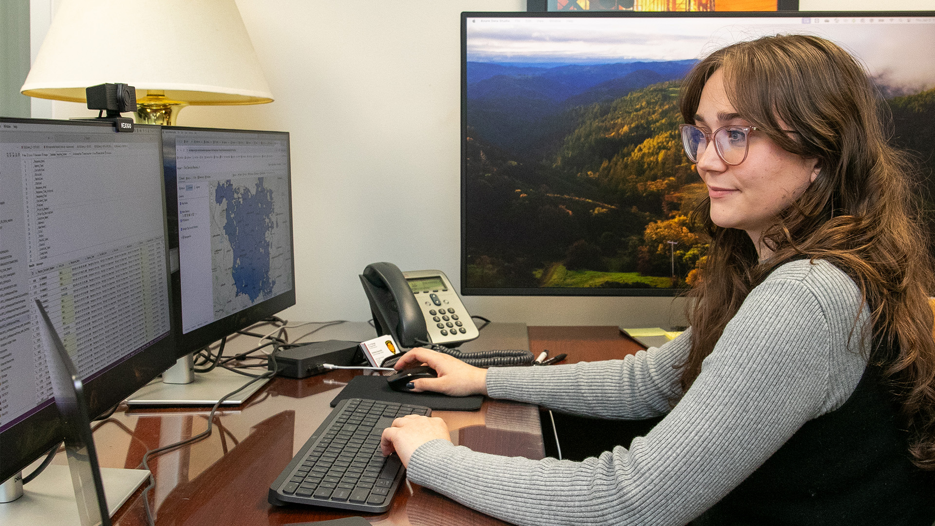 Andrea Saravitz sitting at her computer with multiple monitors.