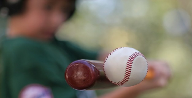 a boy hitting a baseball with a bat