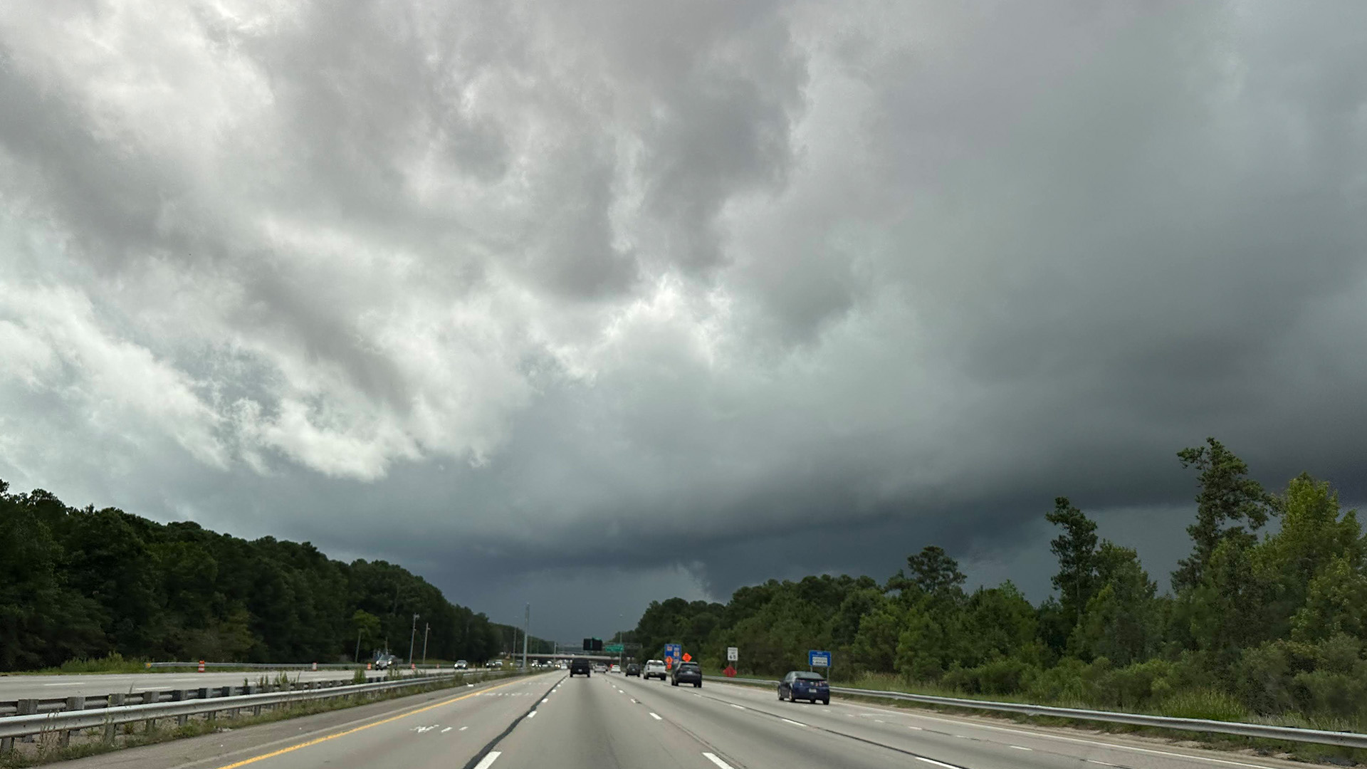 Storm clouds in the distance from perspective of car on a highway