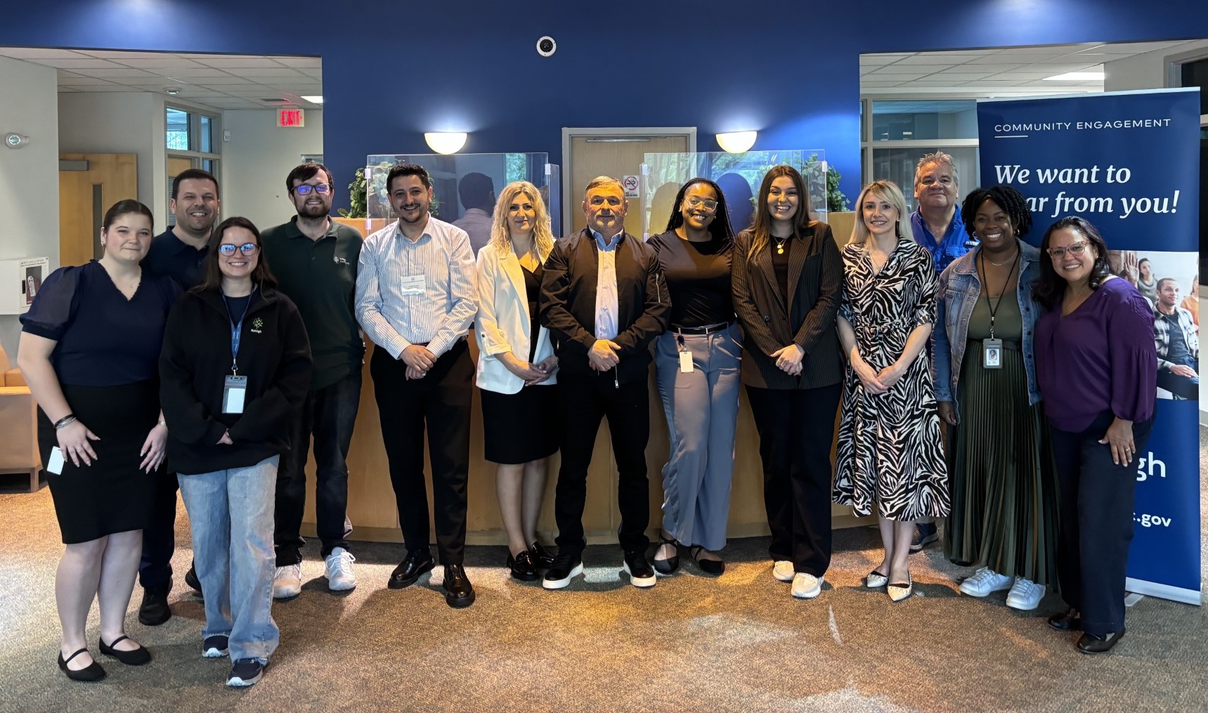 Group of men and women stand beside a sign that reads "Community Engagement"