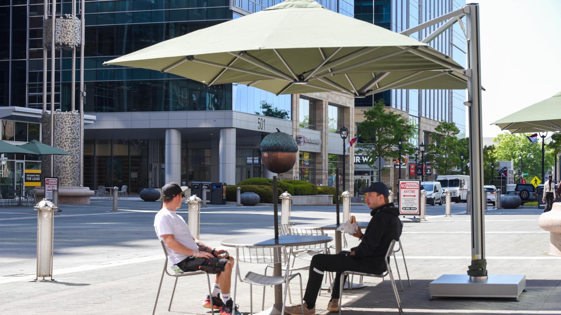 Two people sitting under large umbrella on City Plaza