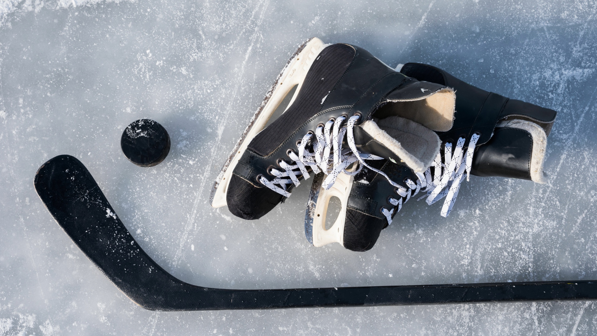 Photo of ice skates and hockey stick laying on ice
