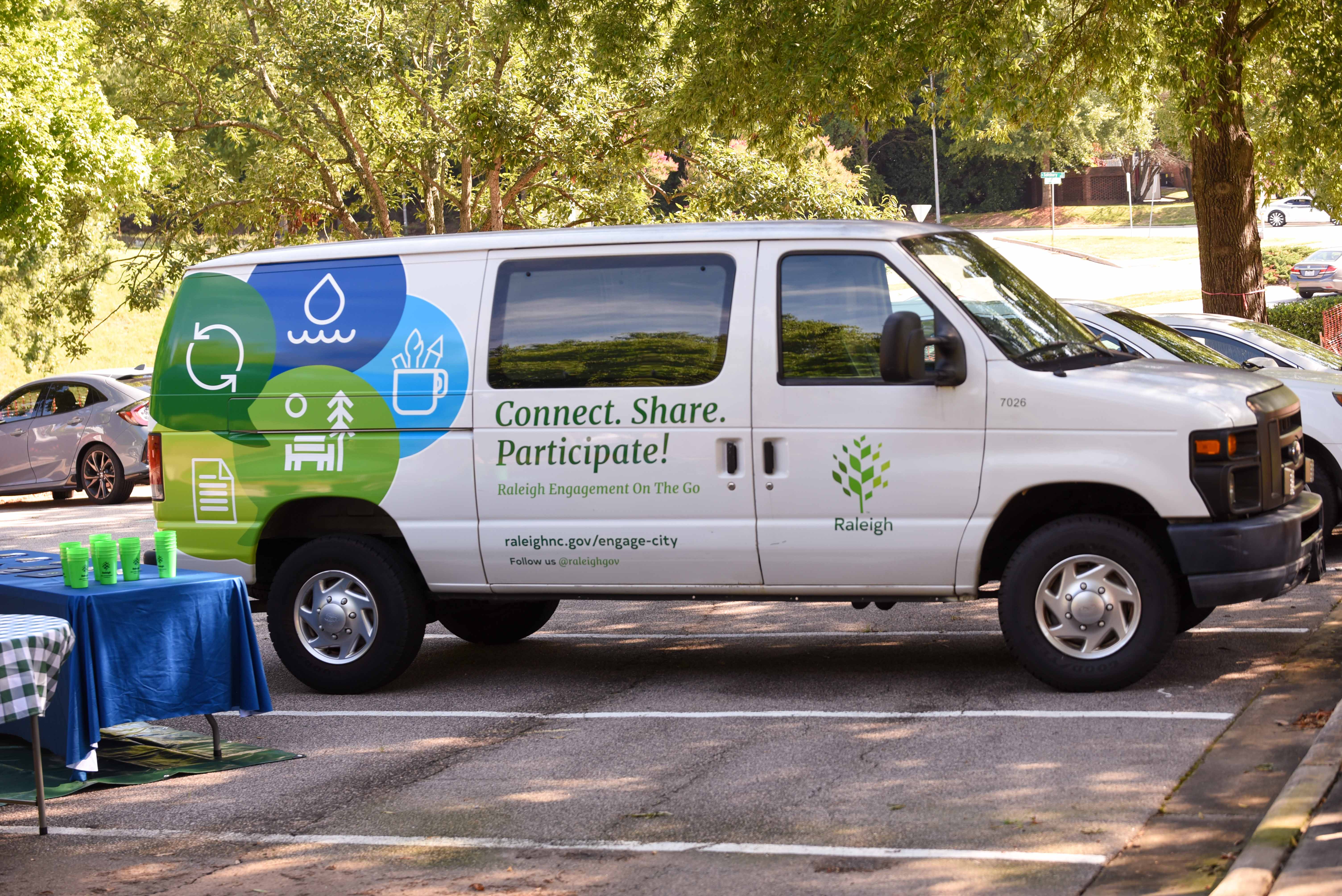 Cargo van with "Connect. Share. Participate" and Raleigh branding parked