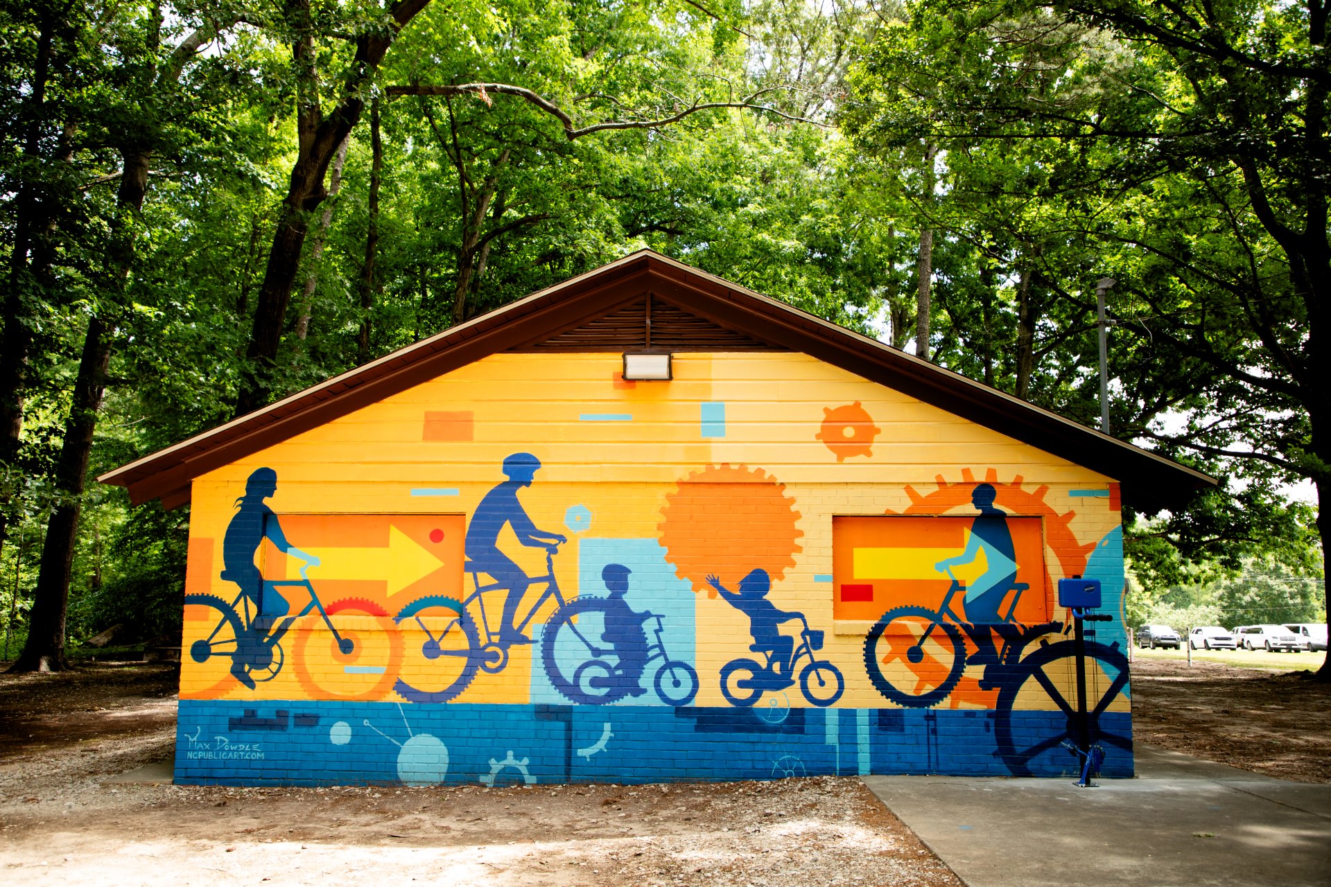 colorful mural of a people riding bikes on a picnic shelter wall. 