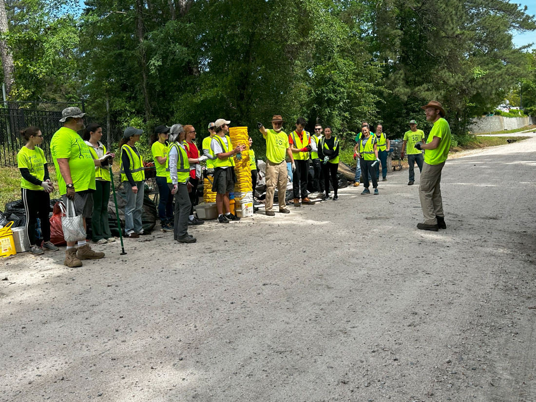 group of people with yellow vests getting safety instructions from a single person infront of group