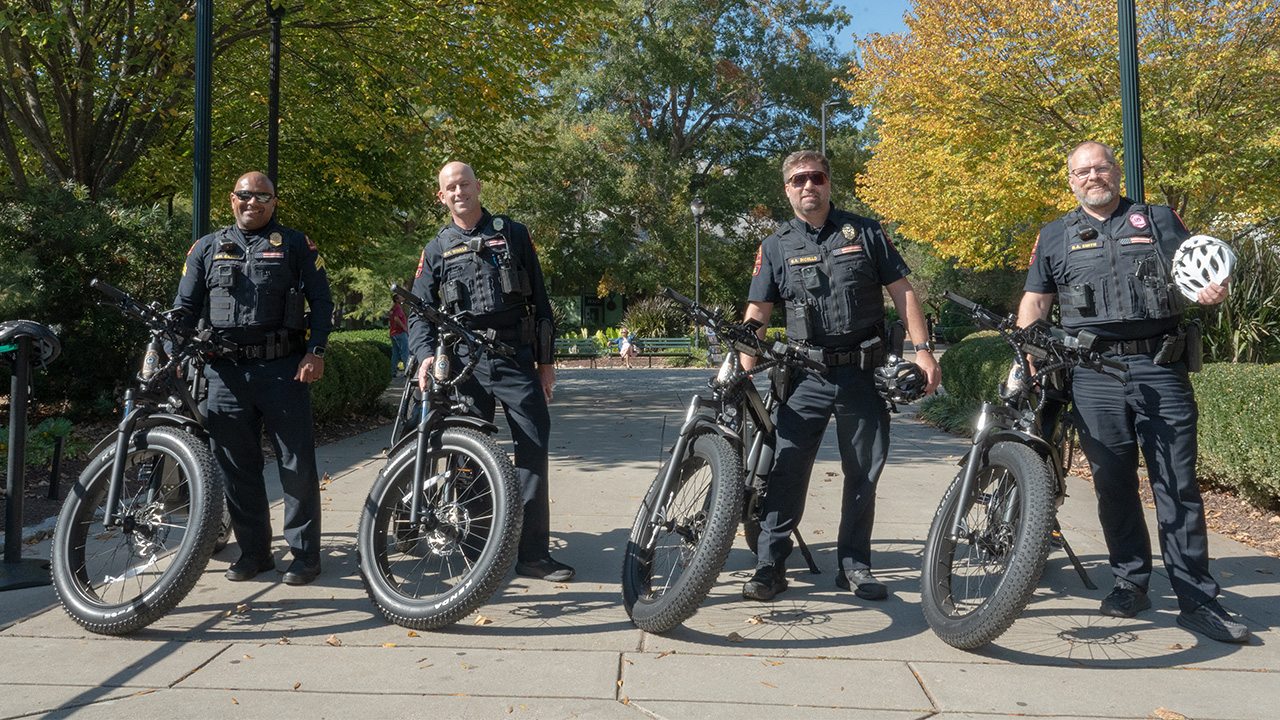Four police officers standing next to their e-bikes