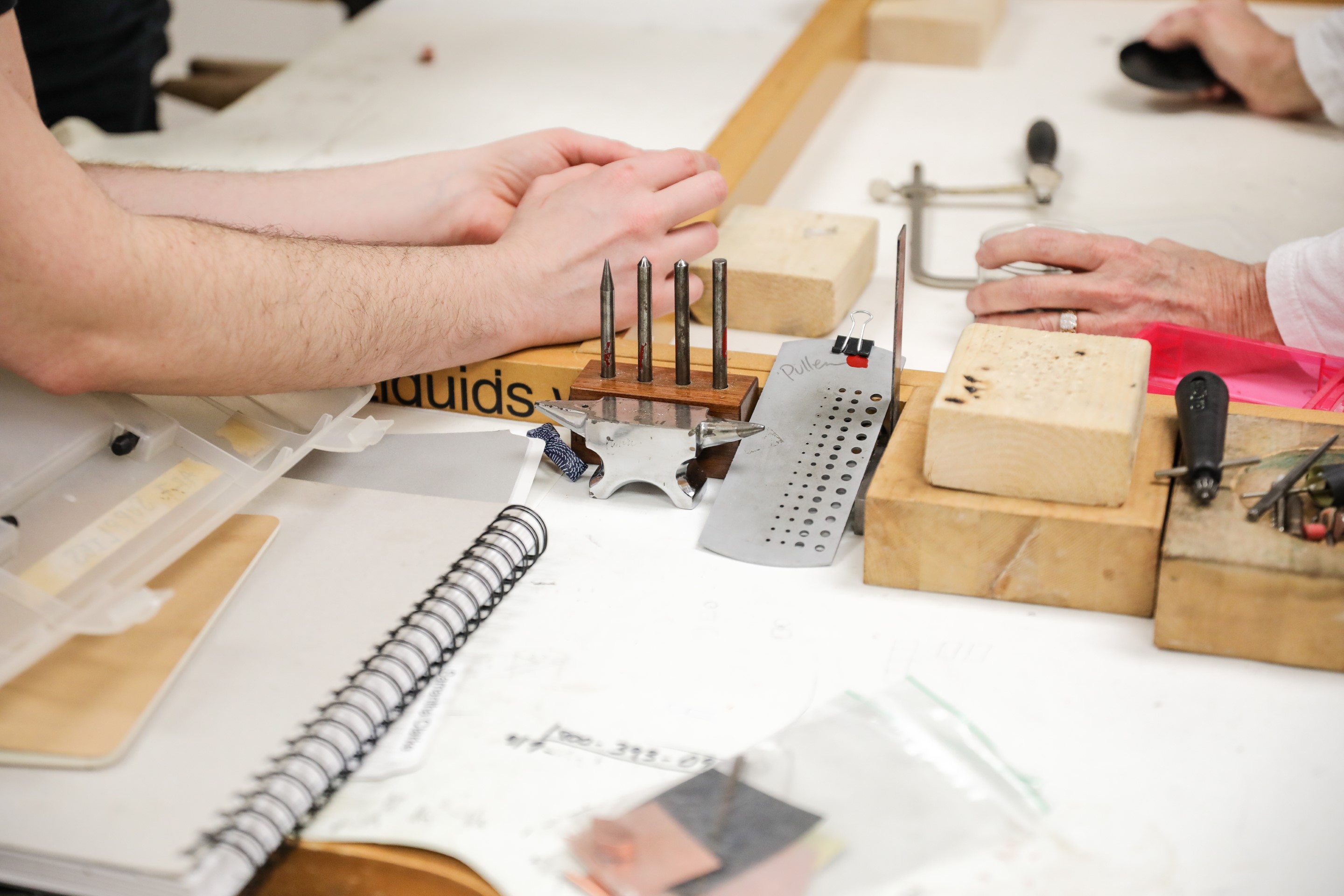Hands working with metal and art supplies in the Sertoma studios. 