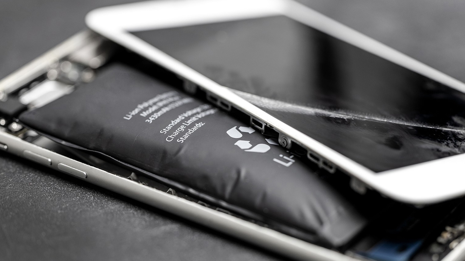 an open mobile phone with a cracked screen and a lithium battery visible from inside the phone