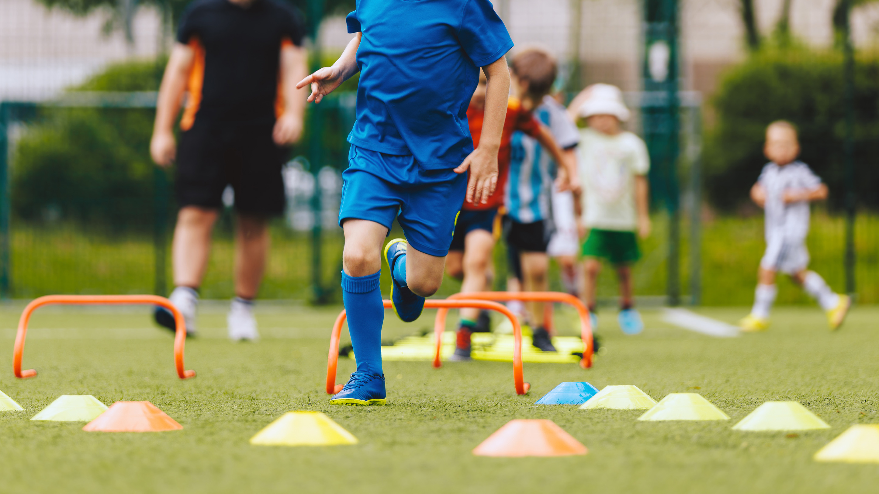 children doing soccer drills with practice cones on a field