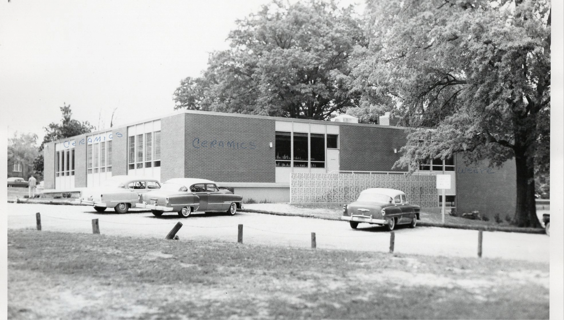 Black and white photo of building with cars in parking lot