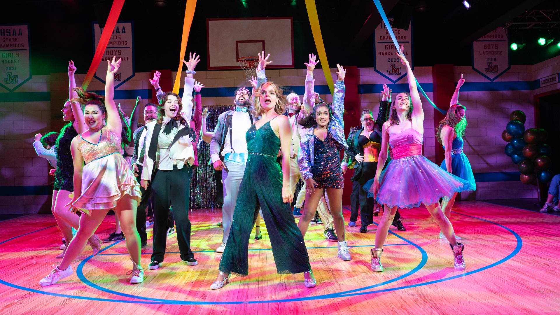 A group of dancers on a basketball court with their hands in the air