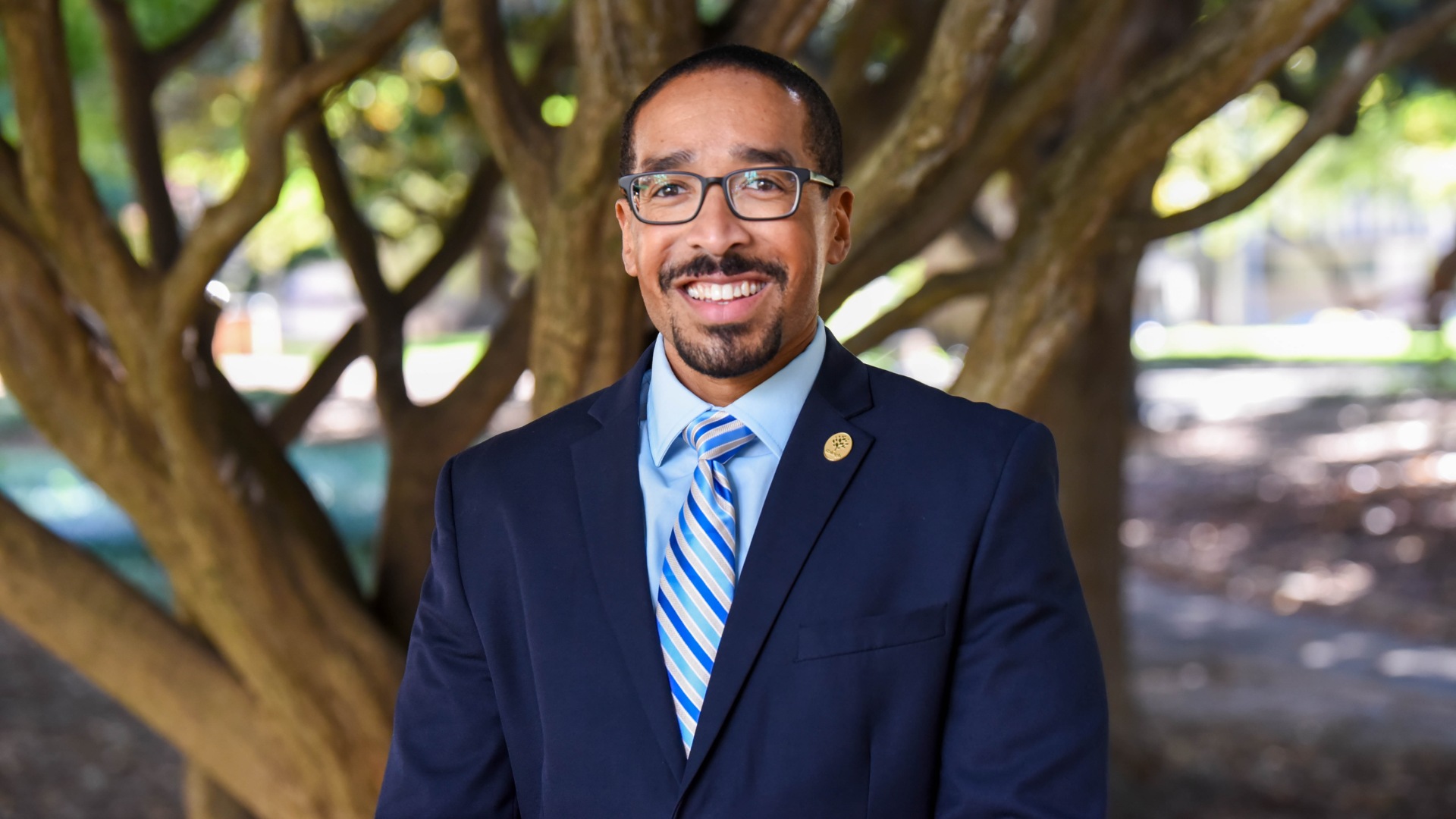 Outdoor portrait of Byron Sanders - tree branches in the background.