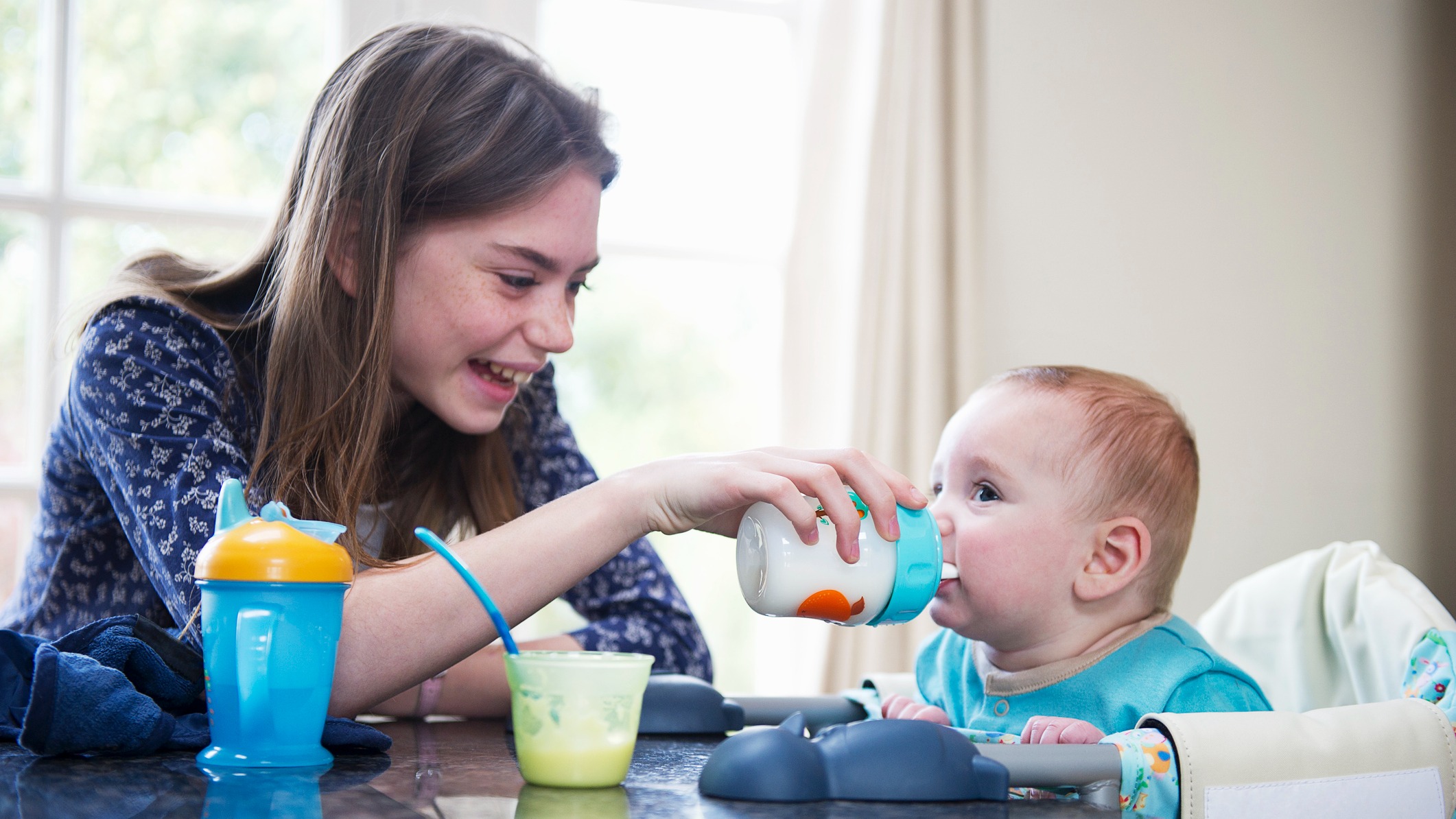 a girl babysitting a baby