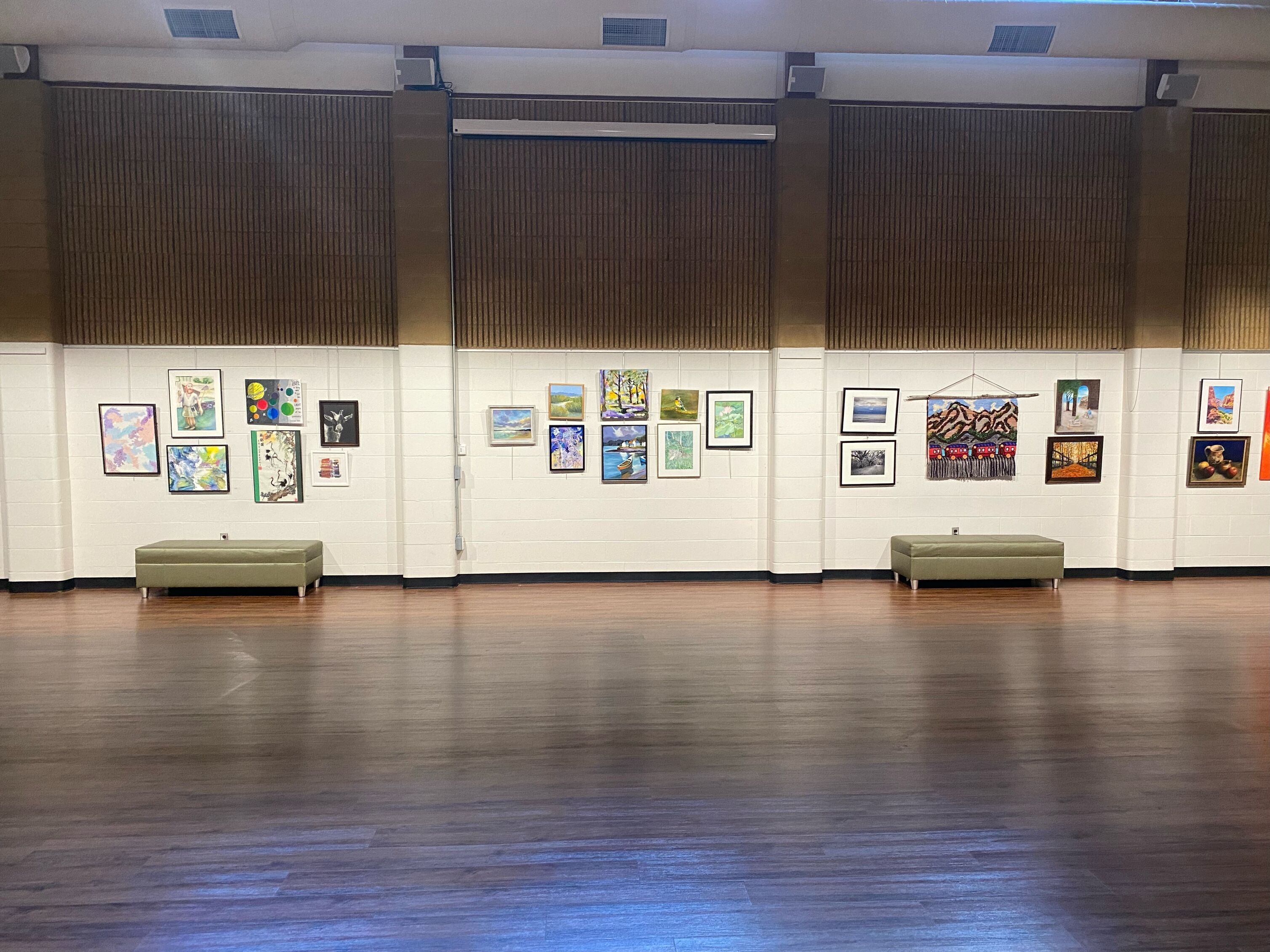 Mix of medium 2-d artworks hanging on a white wall