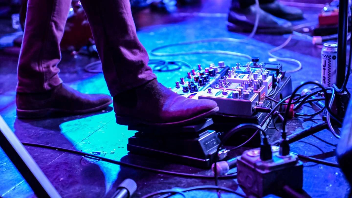 A guitarist stepping on an effects pedal