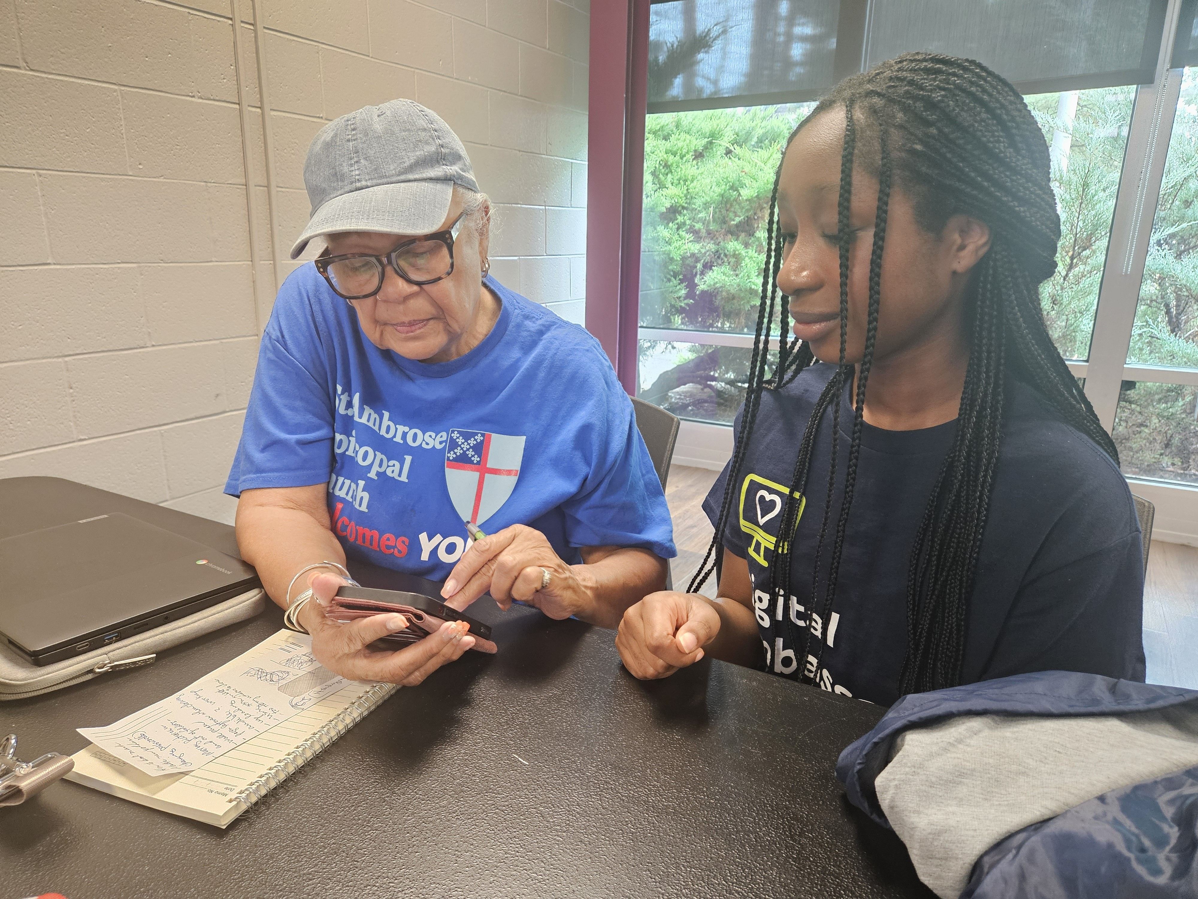 AAYD student helping community member with mobile device