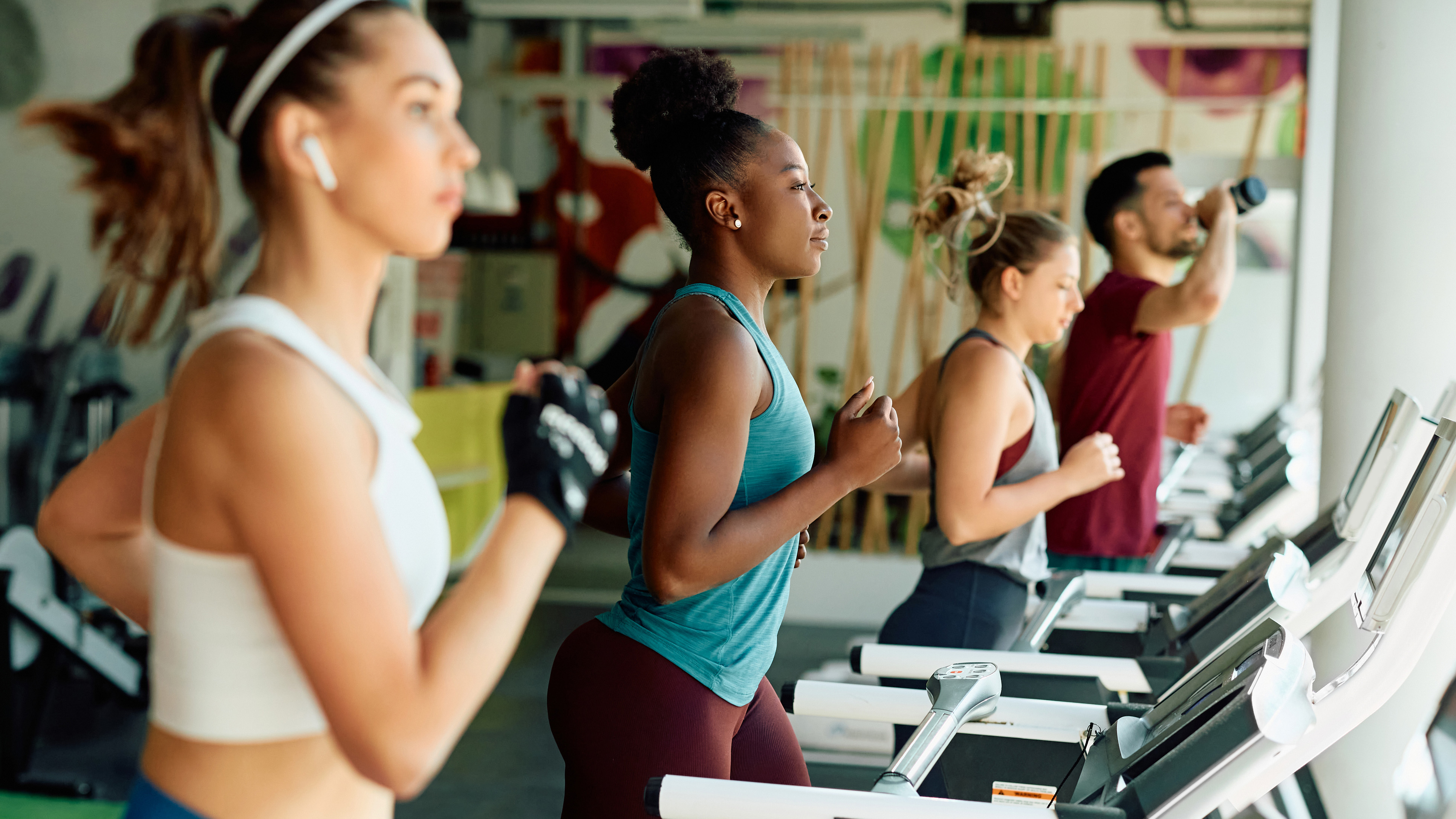 Group of young athletes running on treadmill during sports training in a gym