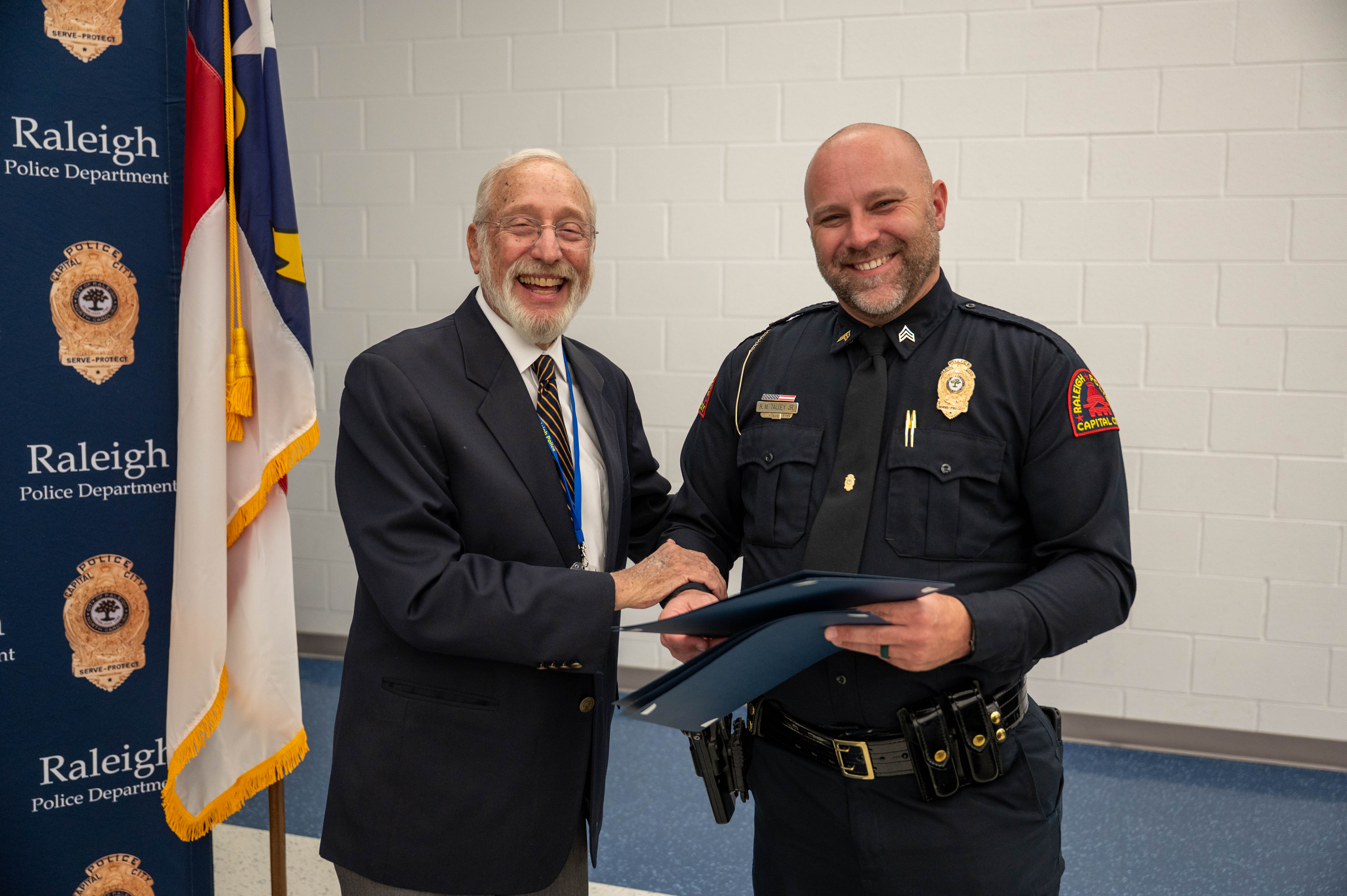 Raleigh police officer handing folder to community member