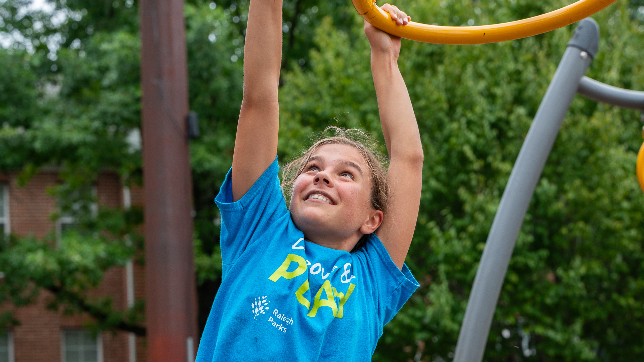 a child on hanging on a play structure at summer camp