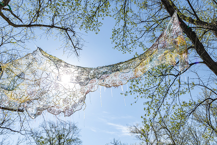 A weaving is suspended above a greenway